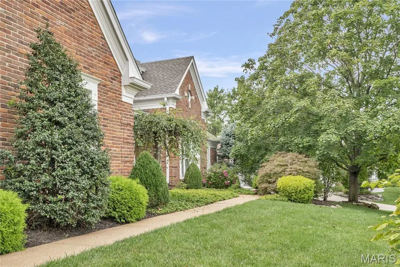 Brick exterior with white trim, featuring a concrete walkway, mature trees, and landscaped shrubbery — 2154 White Lane Drive, Chesterfield, MO 63017