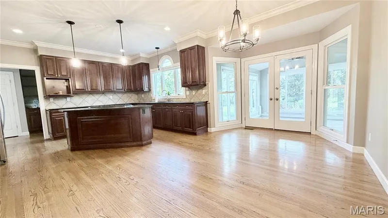Wood-finish flooring, dark wood cabinetry, a kitchen island, and a tile backsplash — 2154 White Lane Drive, Chesterfield, MO 63017
