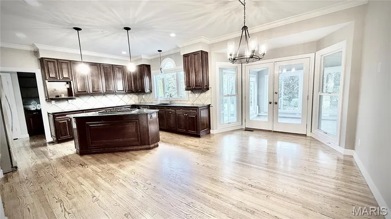 Hardwood flooring throughout, a central island, dark wood-finish cabinetry, recessed lighting, and double glass-paneled doors — 2154 White Lane Drive, Chesterfield, MO 63017