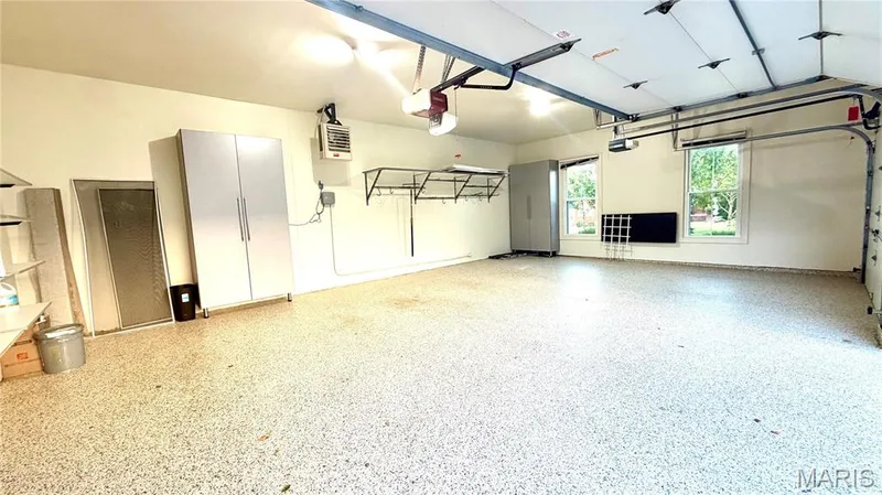 Spacious garage featuring a speckled epoxy floor, dual garage doors, and natural light from two windows — 2154 White Lane Drive, Chesterfield, MO 63017