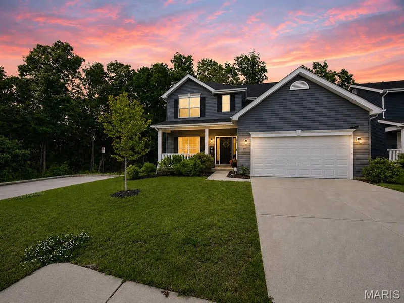 Two-story residence featuring dark siding, a covered front porch, an attached garage, and a concrete driveway — 721 Switchgrass Drive, Wentzville, MO 63385