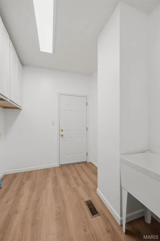 Main floor laundry with vinyl plank flooring, new cabinets, & utility sink — 202 Highland Meadows Drive, Wentzville, MO 63385
