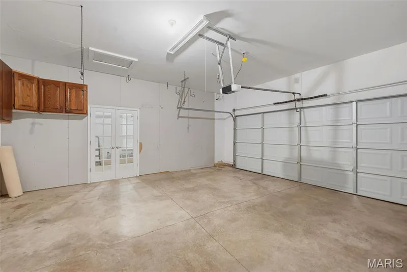 2 car side of garage with lots of storage cabinets and work bench - single car side separated by French doors so it can be used for a work area, etc. — 202 Highland Meadows Drive, Wentzville, MO 63385