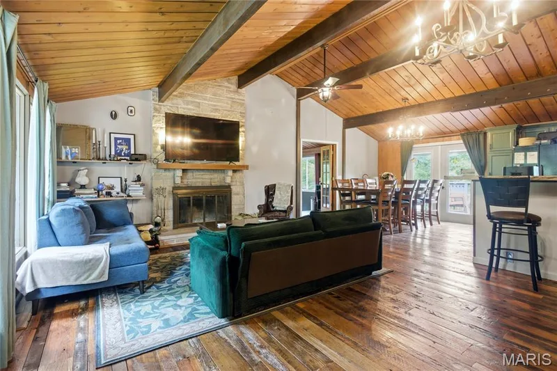 Vaulted wood-paneled ceilings with exposed beams, a stone-faced fireplace, wood-finish flooring, and built-in shelving — 1221 Shepard Road, Wildwood, MO 63038