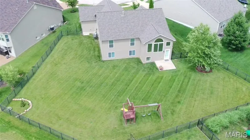 Expansive fenced backyard featuring a level lawn, mature trees, and a concrete patio directly accessible from the residence — 708 Bellingrath Gardens Court, Wentzville, MO 63385
