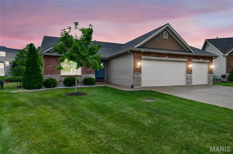 Brick and siding exterior featuring a multi-car garage, stone accents, and a well-maintained lawn — 708 Bellingrath Gardens Court, Wentzville, MO 63385