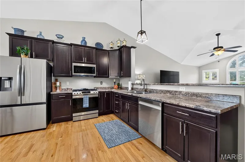 Kitchen featuring rich wood cabinetry, stainless steel appliances, and wood-finish flooring — 708 Bellingrath Gardens Court, Wentzville, MO 63385