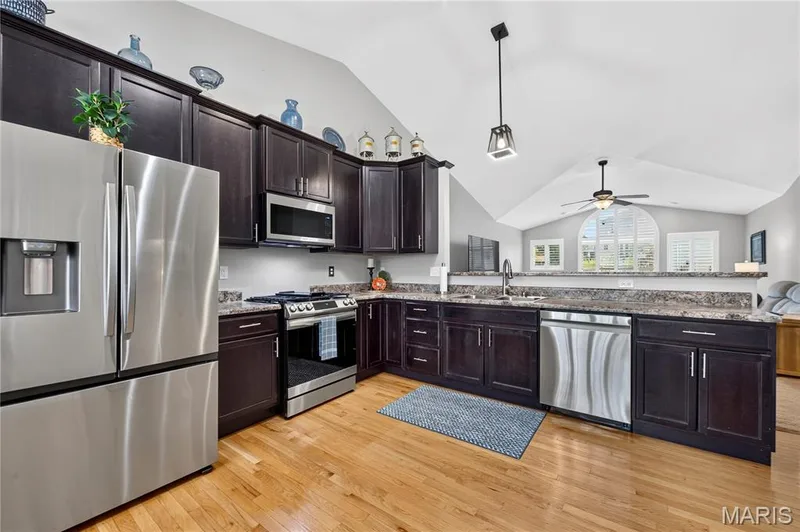 Kitchen featuring stainless steel appliances, dark wood cabinetry, and wood-finish flooring — 708 Bellingrath Gardens Court, Wentzville, MO 63385
