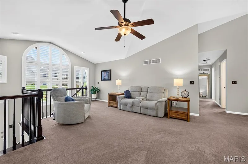 Spacious loft area featuring vaulted ceilings, a ceiling fan, and a large arched window with plantation shutters — 708 Bellingrath Gardens Court, Wentzville, MO 63385