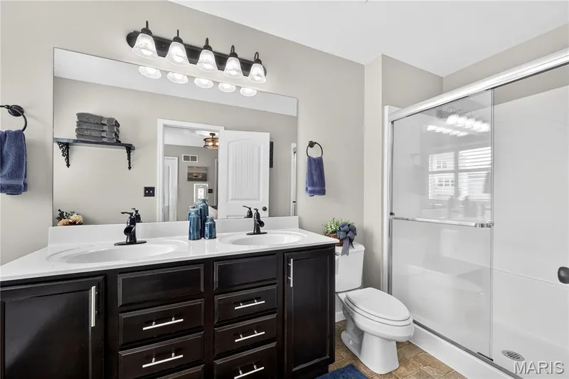 Double vanity with dark wood-finish cabinetry and white countertops — 708 Bellingrath Gardens Court, Wentzville, MO 63385