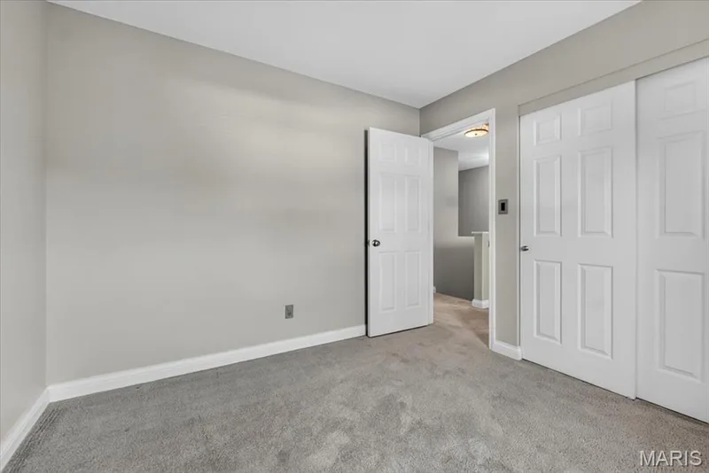 Bedroom featuring light grey walls, white trim, grey carpeting, and sliding panel doors — 115 Carriage View Drive, Wildwood, MO 63040