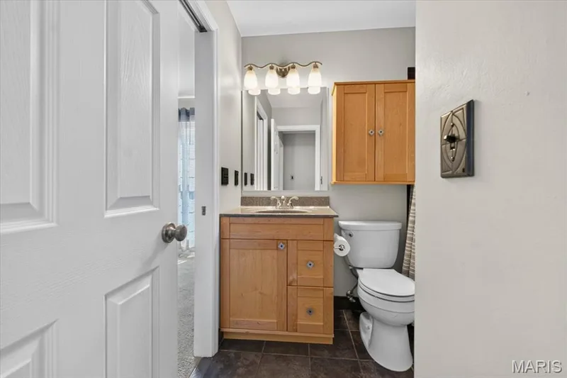 Bathroom featuring a wood-finish vanity with a countertop, an integrated sink, and a mirrored medicine cabinet — 115 Carriage View Drive, Wildwood, MO 63040