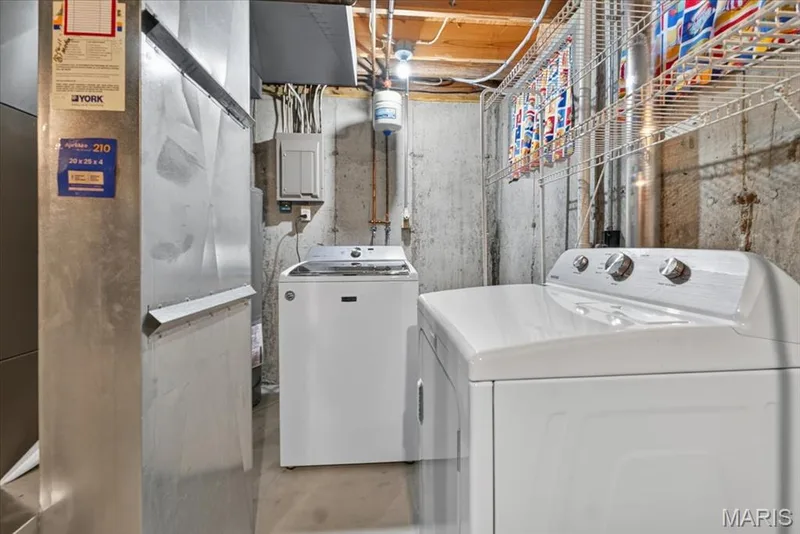 Laundry area featuring concrete walls, exposed ceiling joists, and white wire shelving — 115 Carriage View Drive, Wildwood, MO 63040