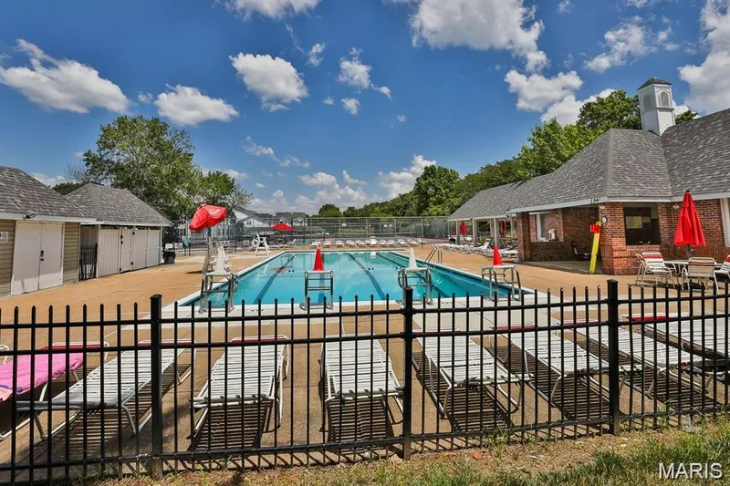 Community swimming pool with dedicated lap lanes and surrounding lounge seating, featuring a brick clubhouse with a cupola and additional changing rooms — 115 Carriage View Drive, Wildwood, MO 63040