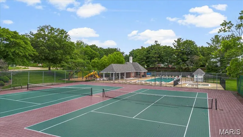 Community recreational area featuring two tennis courts, an outdoor swimming pool, a separate spa, a children's play structure, and a clubhouse with a covered patio — 115 Carriage View Drive, Wildwood, MO 63040