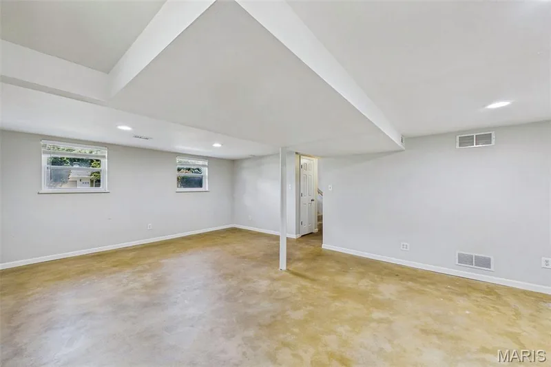 Lower level flex space featuring the HVAC, laundry, garage access, and a spacious secondary living area — 656 Nancy Drive, St Charles, MO 63301