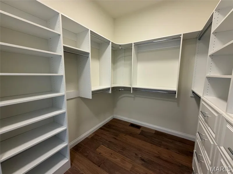 Custom closet system featuring built-in shelving, hanging rods, and integrated drawer storage — Lot 27 Bellevaux Place, St Charles, MO 63301