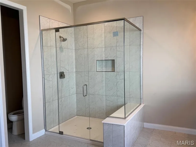 Glass-enclosed shower with a built-in bench, recessed shelf, and tiled walls — Lot 27 Bellevaux Place, St Charles, MO 63301