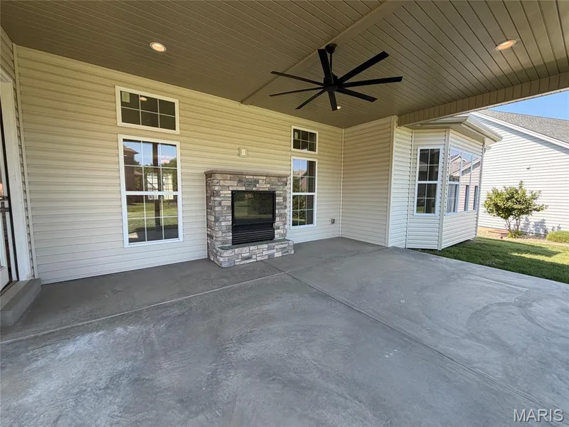 Covered patio featuring a stone-clad see-thru fireplace and a bay window — Lot 27 Bellevaux Place, St Charles, MO 63301