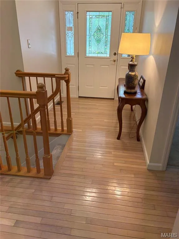 Foyer entry featuring a white paneled door with decorative stained glass, flanked by coordinating sidelights and wood floors — 30 Sterling Pointe Drive #22A, St Charles, MO 63301