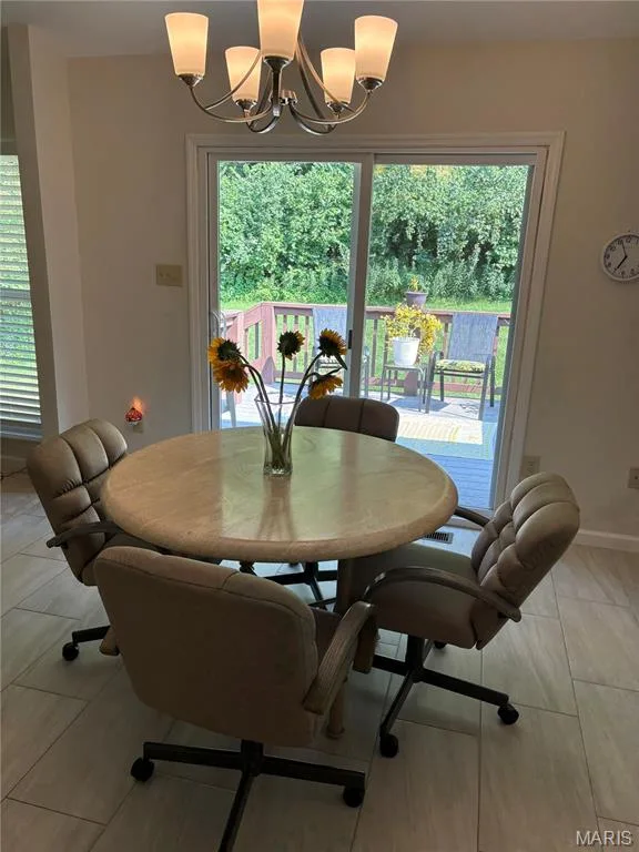 Kitchen space featuring tile flooring, a multi-light chandelier, and a sliding glass door providing direct access to an outdoor deck — 30 Sterling Pointe Drive #22A, St Charles, MO 63301