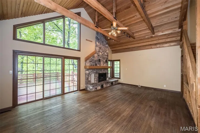 Unfurnished living room featuring hardwood / wood-style floors, high vaulted ceiling, beam ceiling, a stone fireplace, and wood ceiling — 2731 Christy Avenue, Wildwood, MO 63040