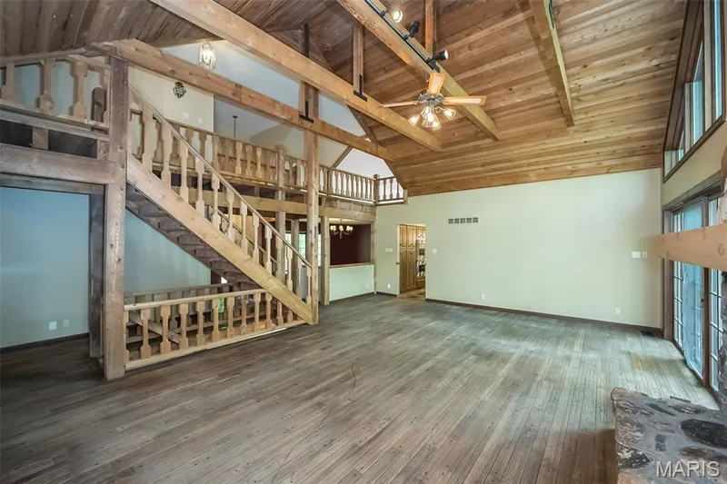 Unfurnished living room featuring baseboards, wooden ceiling, ceiling fan, wood-type flooring, and stairs — 2731 Christy Avenue, Wildwood, MO 63040