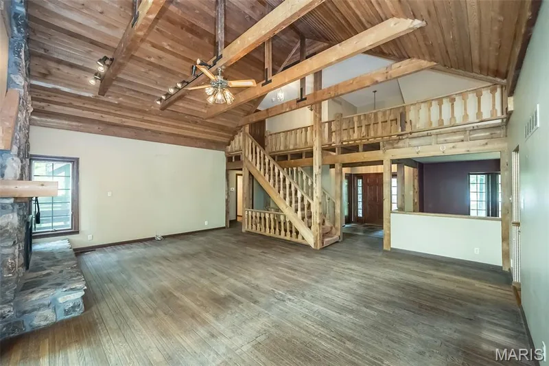 Unfurnished living room featuring high vaulted ceiling, stairs, wooden ceiling, baseboards, and wood-type flooring — 2731 Christy Avenue, Wildwood, MO 63040