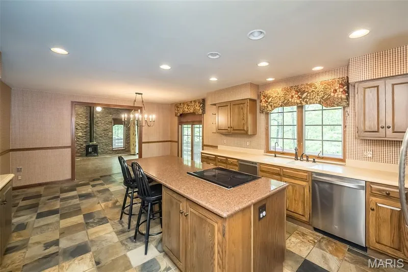 Kitchen featuring stainless steel dishwasher, black electric cooktop, a sink, a wood stove, and a kitchen island — 2731 Christy Avenue, Wildwood, MO 63040