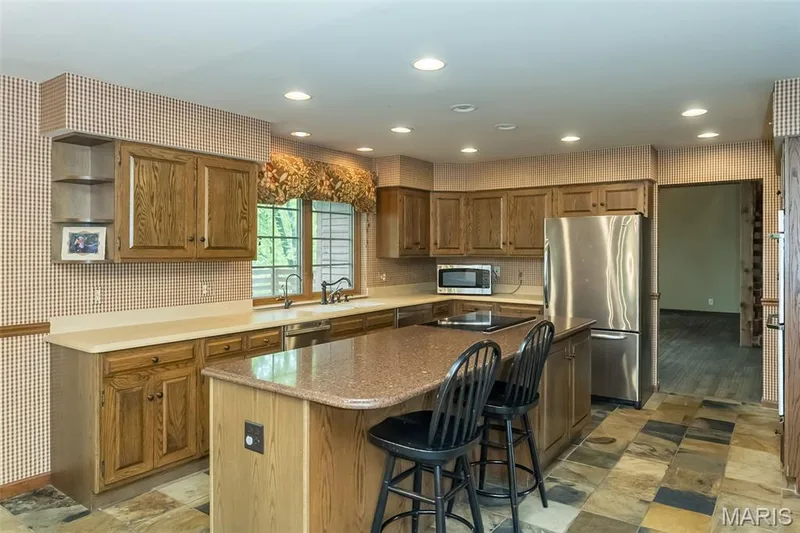 Kitchen with appliances with stainless steel finishes, a kitchen island, open shelves, a breakfast bar, and brown cabinetry — 2731 Christy Avenue, Wildwood, MO 63040