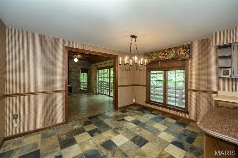 Unfurnished dining area with wallpapered walls, dark stone finish flooring, a chandelier, a ceiling fan, and baseboards — 2731 Christy Avenue, Wildwood, MO 63040