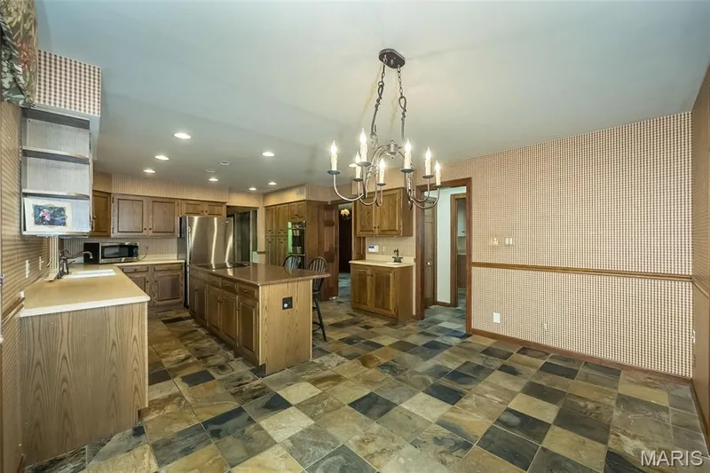 Kitchen featuring appliances with stainless steel finishes, a sink, a kitchen island, dark stone finish floors, and recessed lighting — 2731 Christy Avenue, Wildwood, MO 63040