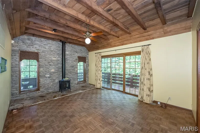 Unfurnished living room with a wood stove, wooden ceiling, ceiling fan, and baseboards — 2731 Christy Avenue, Wildwood, MO 63040