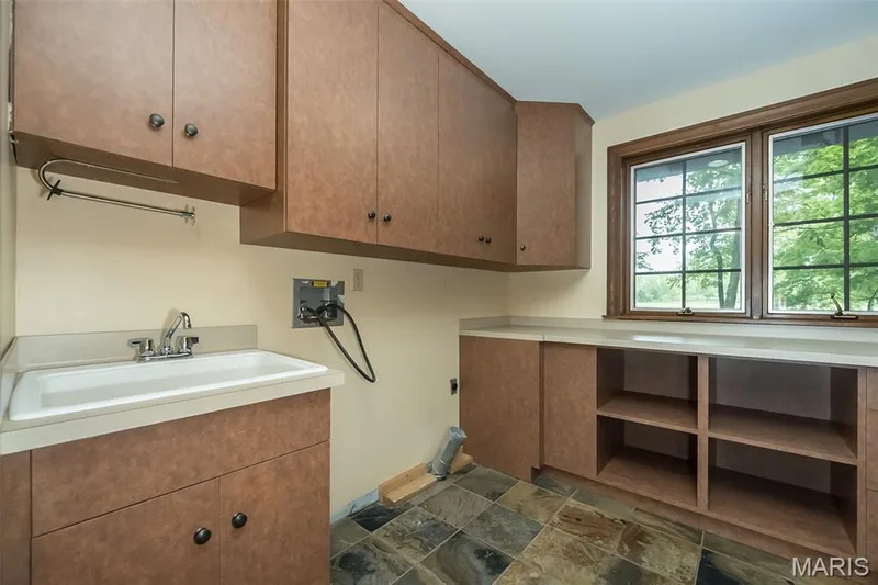 Laundry room featuring cabinet space, hookup for a washing machine, and stone finish floors — 2731 Christy Avenue, Wildwood, MO 63040