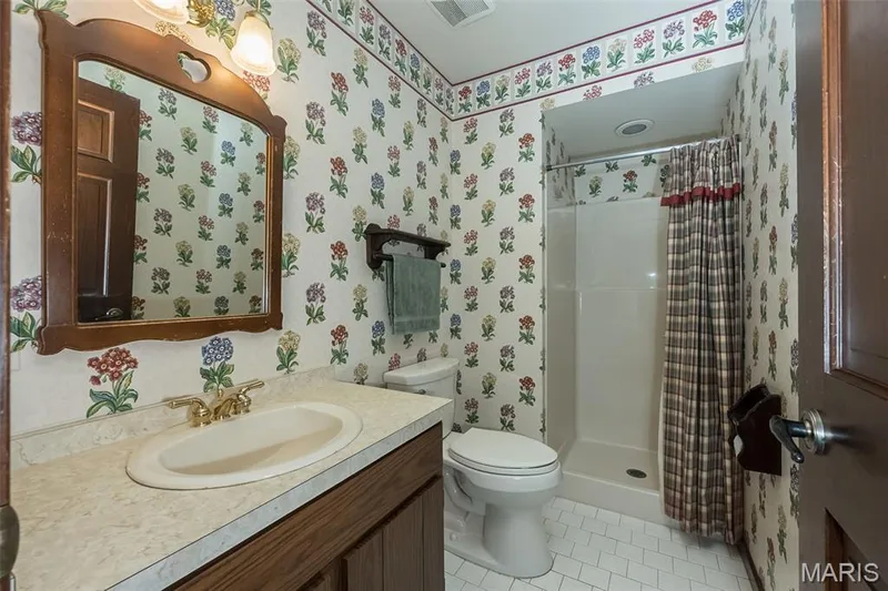 Bathroom with wallpapered walls, tile patterned floors, a stall shower, toilet, and vanity — 2731 Christy Avenue, Wildwood, MO 63040