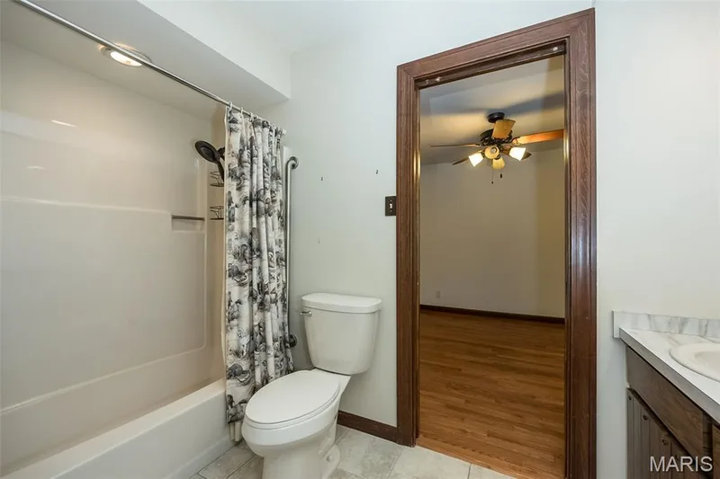 Full bath with a ceiling fan, toilet, vanity, shower / bath combination with curtain, and tile patterned flooring — 2731 Christy Avenue, Wildwood, MO 63040