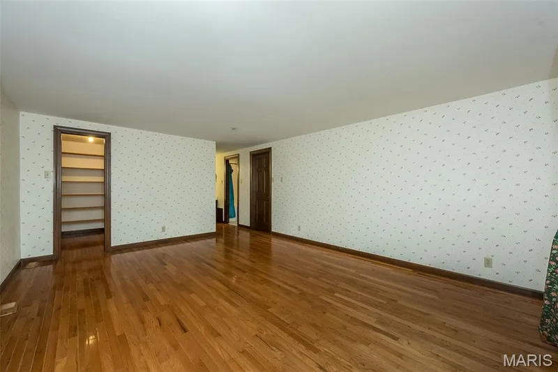 Unfurnished room with wallpapered walls, wood finished floors, and baseboards — 2731 Christy Avenue, Wildwood, MO 63040
