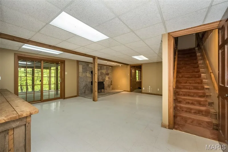 Below grade area with a paneled ceiling, stairway, tile patterned floors, and baseboards — 2731 Christy Avenue, Wildwood, MO 63040