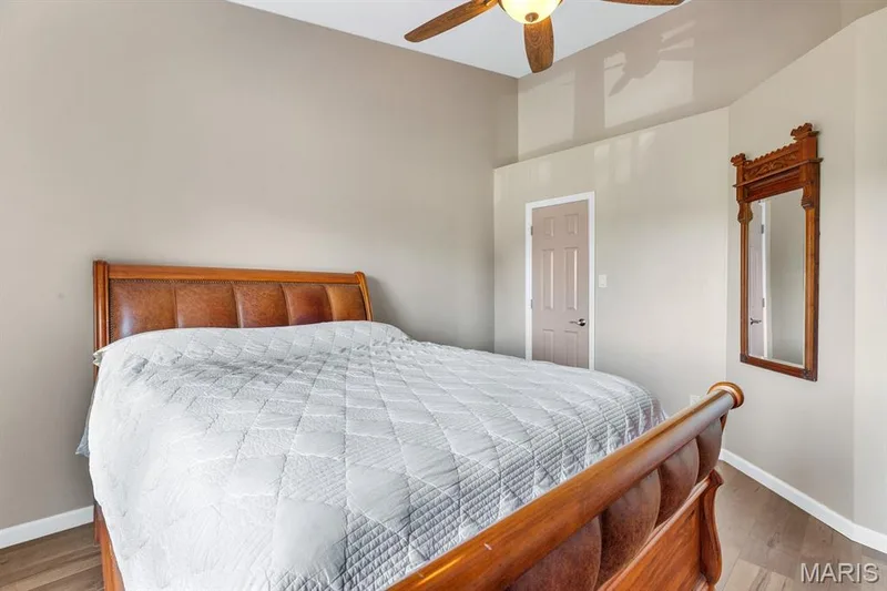 Wood-finish flooring throughout, featuring a neutral wall color, ceiling fan with integrated lighting, and a paneled door with contemporary hardware. HUGE Walk in Closet — 309 Hemingway Lane, Weldon Spring, MO 63304