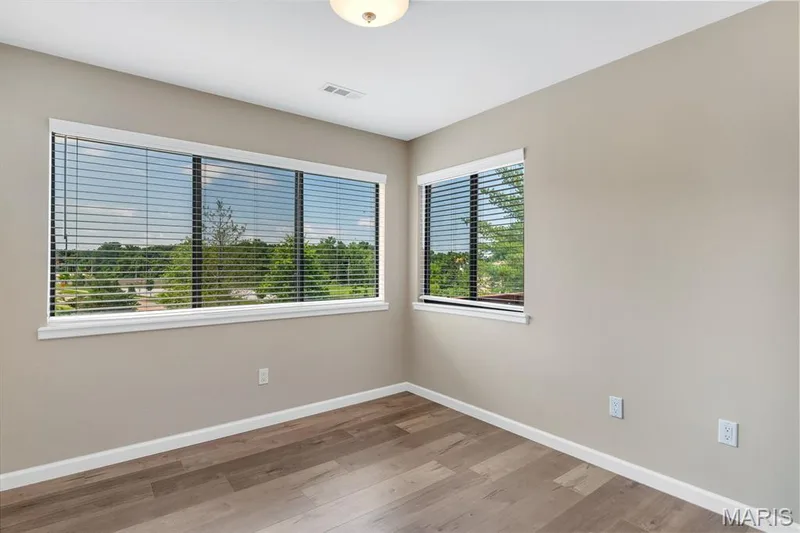Bedroom 2  wood-finish flooring, light beige wall paint, white baseboards, and two windows with horizontal blinds — 309 Hemingway Lane, Weldon Spring, MO 63304