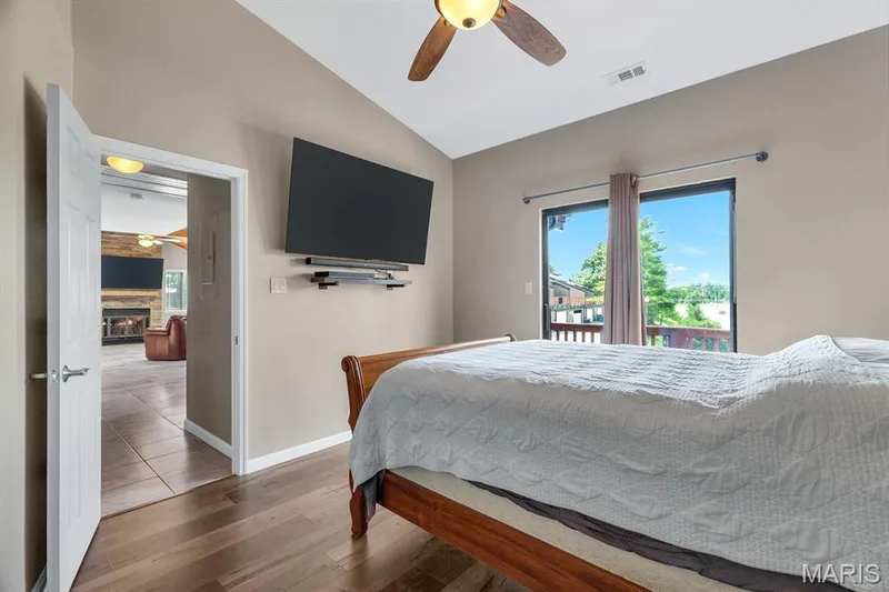 Vaulted ceiling bedroom with wood-finish flooring, a ceiling fan, and sliding glass door access to an outdoor deck — 309 Hemingway Lane, Weldon Spring, MO 63304