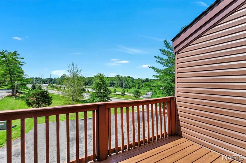 Outdoor balcony featuring wood-finish decking and railing, located off the Primary bedroom — 309 Hemingway Lane, Weldon Spring, MO 63304
