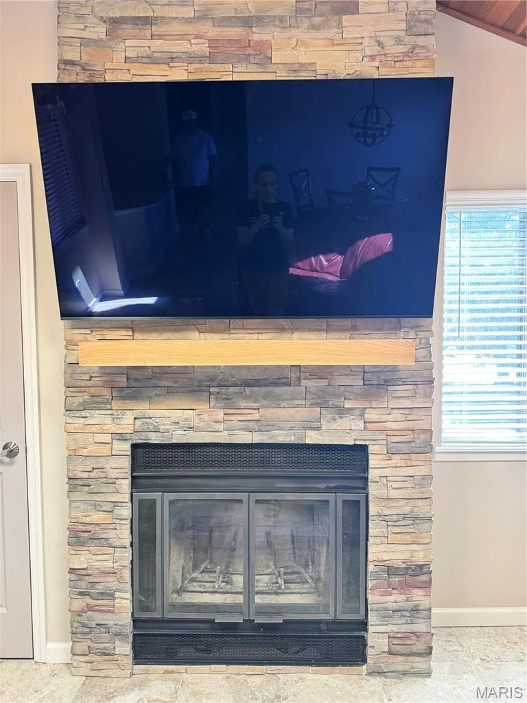 Stacked stone fireplace featuring an integrated wooden mantel and glass doors — 309 Hemingway Lane, Weldon Spring, MO 63304