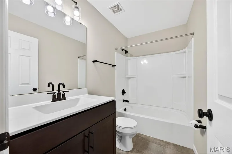 Bathroom featuring a dark wood-finish vanity with a white countertop and integrated sink — 112 Creek Haven Court, Lake St. Louis, MO 63367