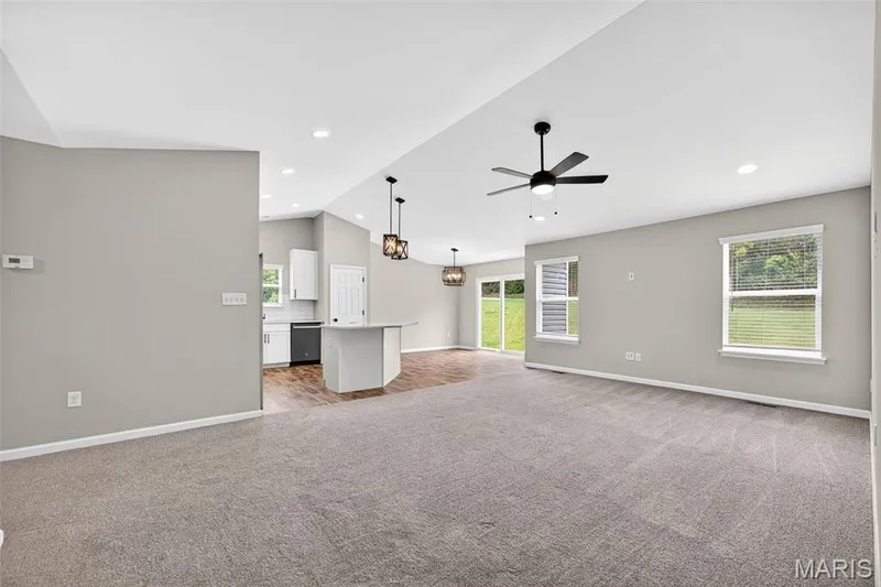 Spacious open-concept living area featuring soft gray walls and gray carpeting — 112 Creek Haven Court, Lake St. Louis, MO 63367