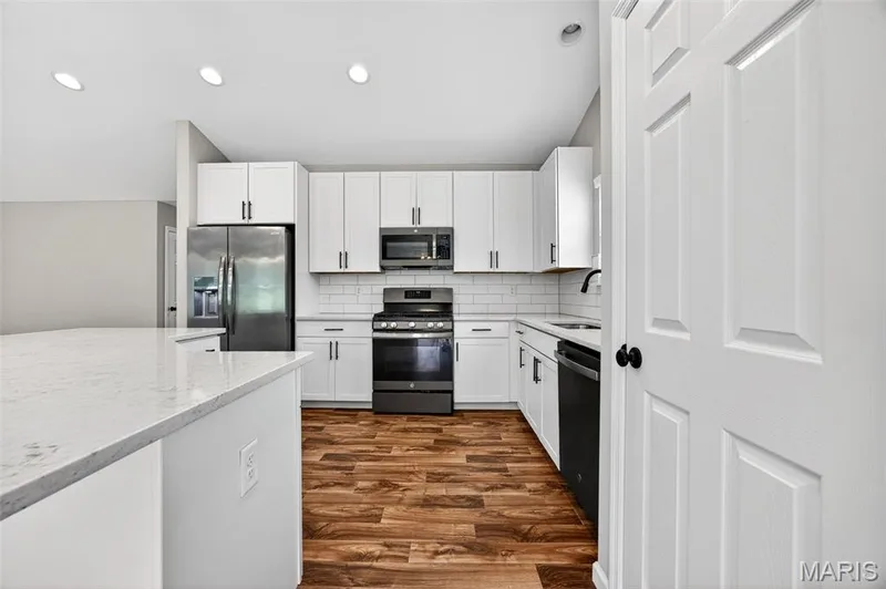 Kitchen featuring white shaker-style cabinetry with dark hardware, a subway tile backsplash, and dark wood-finish flooring — 112 Creek Haven Court, Lake St. Louis, MO 63367