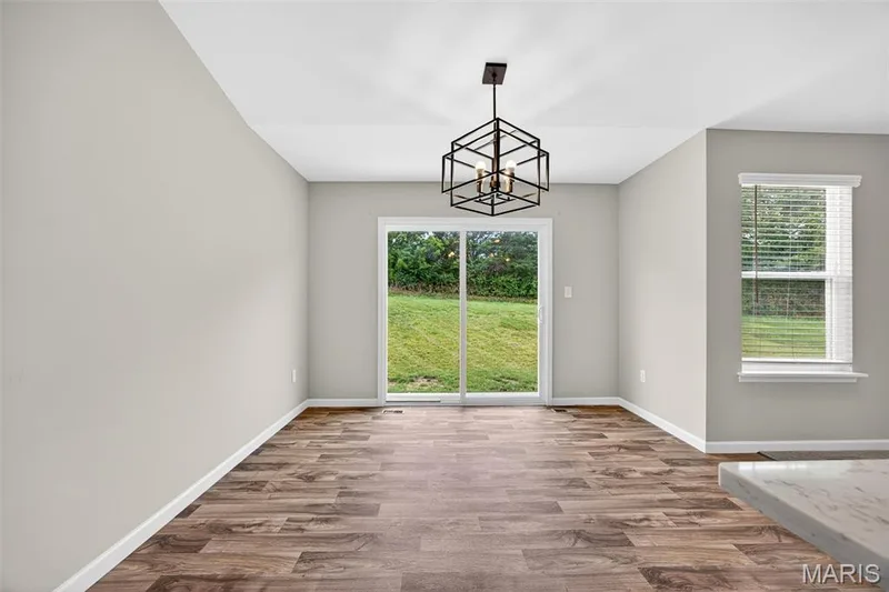 Spacious room featuring wood-finish flooring, light gray wall tones, and a contemporary geometric chandelier — 112 Creek Haven Court, Lake St. Louis, MO 63367