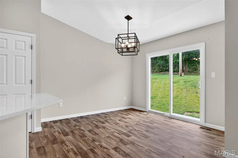 Dining area featuring wood-finish flooring and a contemporary geometric chandelier — 112 Creek Haven Court, Lake St. Louis, MO 63367