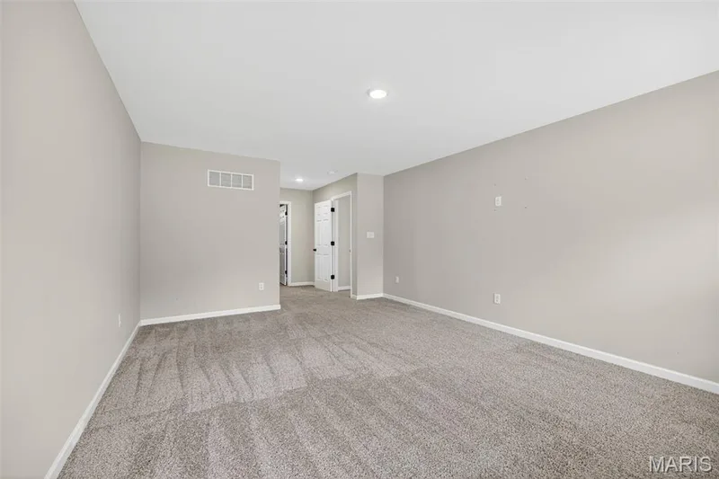 Spacious carpeted room featuring light gray walls, white trim, recessed lighting, and white panel doors — 112 Creek Haven Court, Lake St. Louis, MO 63367