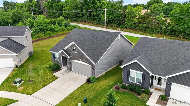 Modern single-story home featuring a dark gray brick facade with white trim, an attached two-car garage, and a concrete driveway — 112 Creek Haven Court, Lake St. Louis, MO 63367